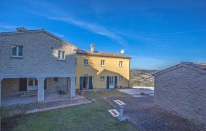 a large yellow house with a brick yard at Il Ristoro Del Viandante in Offagna