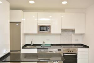 a white kitchen with a sink and a microwave at 4Torres Homes - Sofía in Madrid