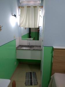 a green and white bathroom with a sink and a mirror at POUSADA DOS AMIGOS in Presidente Venceslau