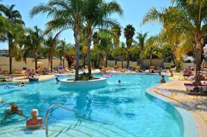 a swimming pool with people in a resort with palm trees at Mirachoro Carvoeiro in Carvoeiro