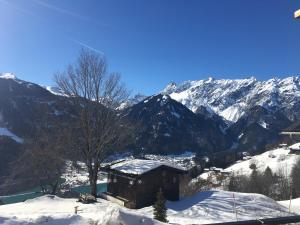 a cabin in the snow with mountains in the background at Kleines Paradies Montafon in Bartholomäberg