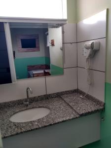 a bathroom with a sink and a phone in a mirror at POUSADA DOS AMIGOS in Presidente Venceslau +59 photos
