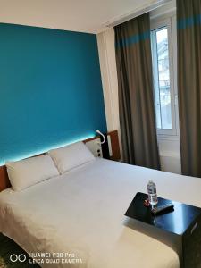 シャンベリにあるIbis Styles Chambery Centre Gareの白いベッドと青い壁が備わるホテルルームです。