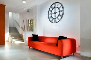 a red couch in a living room with a clock on the wall at Hotel Rubens in Rimini
