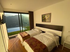 two beds in a room with a large window at Casa de Ribadouro in Baião +91 photos
