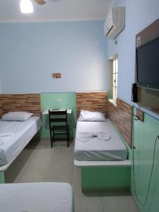 a room with two beds and a flat screen tv at POUSADA DOS AMIGOS in Presidente Venceslau