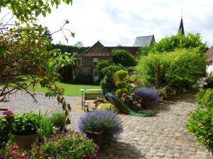 un jardín con flores, un banco y una iglesia en Manoir Francis en Marles-sur-Canche