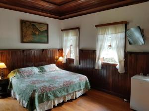 um quarto com uma cama e duas janelas em Hotel Fazenda São Moritz em Teresópolis
