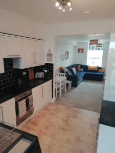 a kitchen and living room with a blue couch at Rhodri Apartment with Sea Views and Sun Terrace in Trearddur