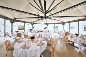 un comedor con mesas y sillas blancas y ventanas en Hotel Skovpavillonen en Kerteminde