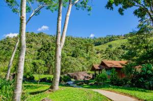 a path through a forest with a house and trees at Pousada Recanto Do Kaléo in Visconde De Maua