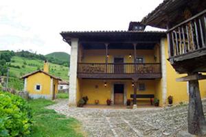 a yellow house with a balcony on the side of it at La Corrolada in Avín