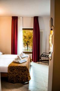Hotel Corte Dal Castello في كولا دي لاتيزي: غرفة نوم بسرير ونافذة ذات ستائر حمراء