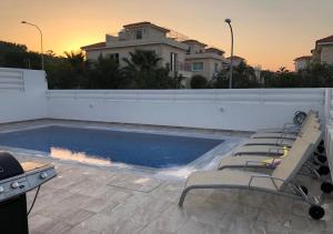 - une piscine avec des chaises longues en face d'une maison dans l'établissement Villa Ioli Green Bay by TrulyCyprus, à Protaras