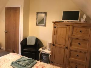 a bedroom with a dresser with a television and a chair at 28 Hillside in Lochinver