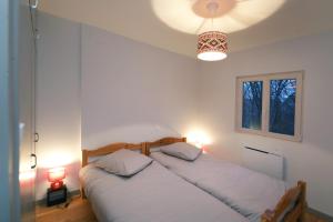 two beds in a white bedroom with two lamps at Chalet les airelles in Labaroche