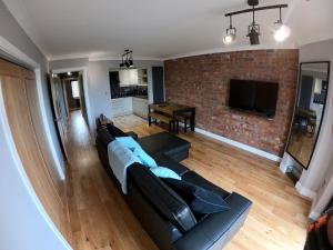 a living room with a black couch and a brick wall at 46 Y Lanfa in Aberystwyth
