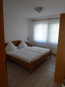 um quarto com uma cama com lençóis brancos e uma janela em Ferienwohnung Sewenig em Müden