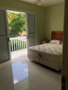 Schlafzimmer mit einem Bett und einer Tür zu einem Balkon in der Unterkunft Casa em Pauba in São Sebastião