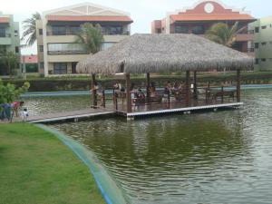 un restaurant avec un toit de paille sur l'eau dans l'établissement Aquaville Resort Porto Das Dunas block 63, à Aquiraz