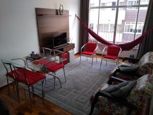 a living room with a glass table and red chairs at Ensolarado ao lado do shopping com garagem e Wifi in Teresópolis