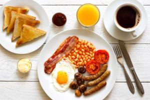 un plato de desayuno con huevos salchichas y tostadas en Road Stay, en Maseru