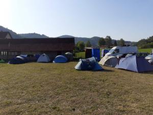 a group of tents in a field next to a building at Dragacevska avlija - Camp in Guča