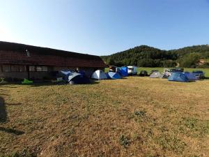 a group of tents in a field next to a barn at Dragacevska avlija - Camp in Guča