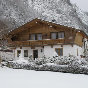 a house covered in snow in front of a mountain at Appartement Top Tirol in Maurach