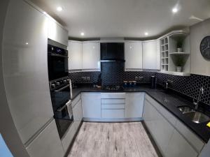 uma cozinha com armários brancos e um forno com placa de fogão em 46 Y Lanfa em Aberystwyth