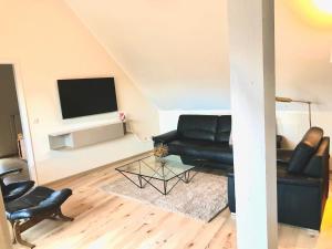 ein Wohnzimmer mit einem schwarzen Sofa und einem TV in der Unterkunft Ferienappartements Bergen in Steinhude