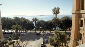 a view of a parking lot with palm trees and the ocean at La Maison in Taranto