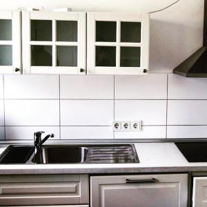 cocina con fregadero y armarios blancos en Cosyhome Apartment, en Hannover