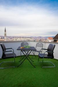 ORA-PRN,cosy apartment in the city center في بريشتيني: طاولة وكراسي على شرفة مع عشب أخضر