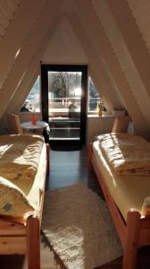 a attic room with two beds and a window at Ferienhaus Mauer Krombachtalsperre, exclusive Nebenkosten Strom in Driedorf