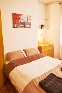 a bedroom with a bed and a painting on the wall at Home In Queen's Park in London