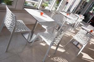 a white table and chairs in a room with windows at Hotel Rubens in Rimini