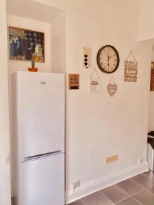 een witte koelkast in een kamer met een klok aan de muur bij Spacious two bedroom flat, central location in Plymouth +8 foto's