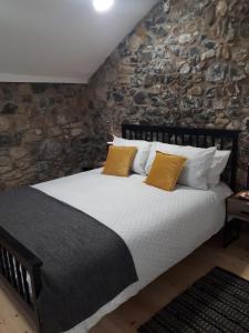 een slaapkamer met een groot bed en een stenen muur bij The Stonehouse, in the heart of Ballycastle in Ballycastle