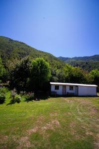 Un edificio blanco en un campo con montañas al fondo. en Hospedaje Familiar Nicomacc, en Melipeuco