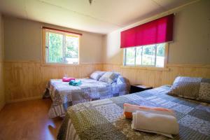 una habitación con dos camas y dos ventanas en Hospedaje Familiar Nicomacc, en Melipeuco