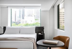 a bedroom with a bed and a table and a window at Lancemore Crossley St. Melbourne in Melbourne