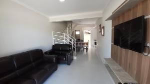 a living room with a couch and a flat screen tv at sobrado Bege - Mariscal in Bombinhas