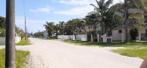 a dirt road with palm trees on the side of a house at sobrado Bege - Mariscal in Bombinhas