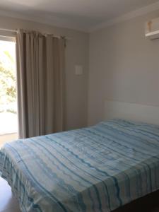 a bed in a bedroom with a window at sobrado Bege - Mariscal in Bombinhas