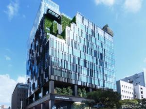 a tall glass building with green vegetation on it at Miyako Hotel Hakata in Fukuoka