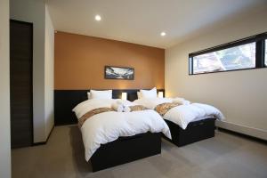 a bedroom with two beds and a window at Snowlines Apartments Hakuba in Hakuba +20 photos