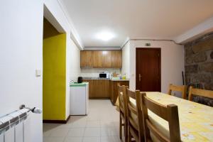 eine Küche mit einem Tisch und Stühlen sowie einem Kühlschrank in der Unterkunft Casas do Flor in Gouveia