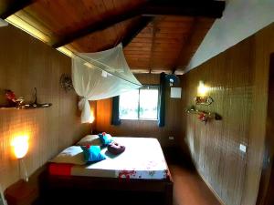 PaopaoにあるEco Lodge Village Temanohaの小さなお部屋で、ベッド1台(傘付)が備わります。