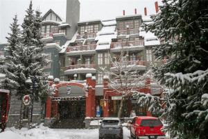 un bâtiment recouvert de neige avec des voitures garées devant dans l'établissement Alpenglow Lodge by Bill, à Whistler